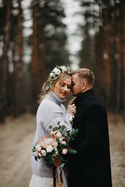 A friss házasok az erdei ösvényen ölelkeznek fenyőfák között, tűlevelű erdőben. Közelkép. - Fotó, kép