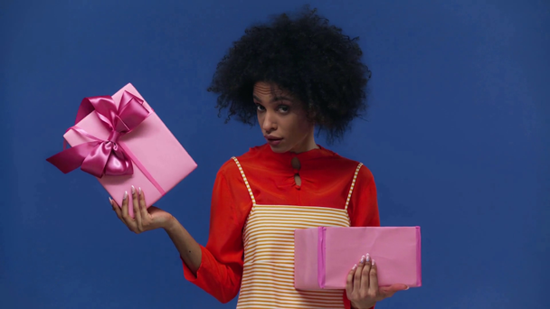 enttäuschte afrikanisch-amerikanische Mädchen eröffnet Geschenk isoliert auf blau - Filmmaterial, Video
