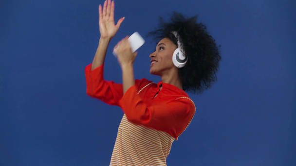 feliz afroamericano chica escuchando música aislado en azul
 - Metraje, vídeo