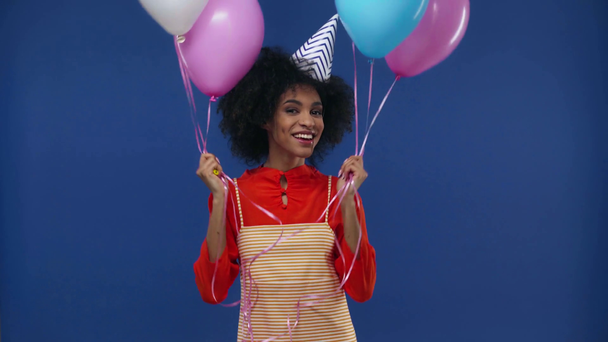 щаслива афроамериканська дівчина тримає повітряні кулі ізольовані на синьому
 - Кадри, відео