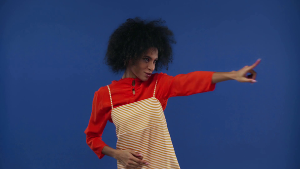cheerful african american girl dancing isolated on blue - Felvétel, videó