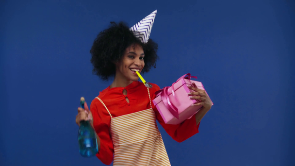 afro-amerikai lány ajándékkal és üveggel elszigetelve a kék - Felvétel, videó