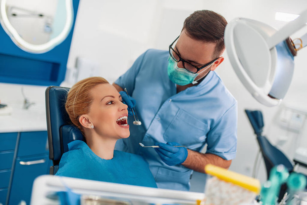Dentysta badający zęby pacjenta w gabinecie stomatologicznym.Ludzie, stomatologia i koncepcja opieki zdrowotnej. - Zdjęcie, obraz