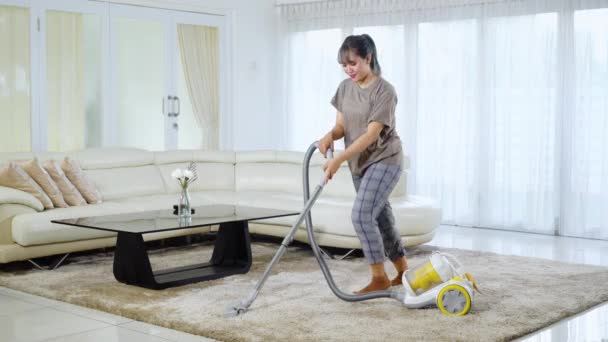 Bonito tapete de limpeza dona de casa com um aspirador de pó enquanto dança na sala de estar em casa. Tiro em resolução 4k
 - Filmagem, Vídeo