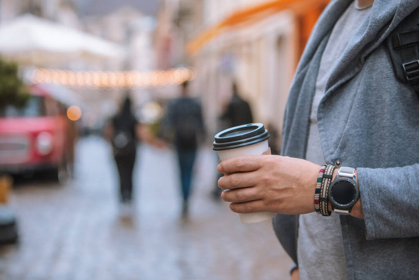 Mann Hand aus nächster Nähe hält Einweg-Kaffeetasse Smart Watch mit Armband am Handgelenk - Foto, Bild