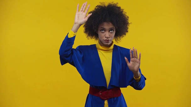 mujer afroamericana golpeando y haciendo gestos aislados en amarillo
  - Metraje, vídeo