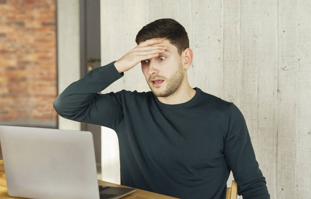 Überlasteter Mitarbeiter schaut schockiert auf Laptop im Büro - Foto, Bild