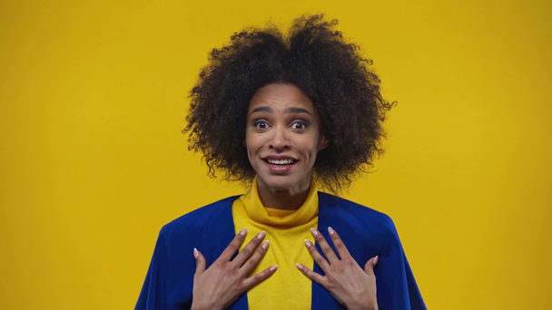 überraschte Afroamerikanerin lächelt isoliert auf gelb  - Filmmaterial, Video