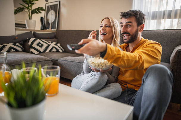 Portrait of happy couple enjoying at home and watching television together.Couple preparing to watch a movie. - Fotó, kép