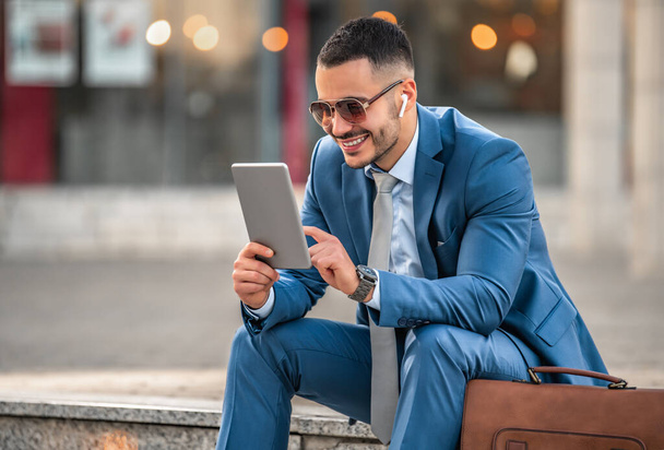 Aantrekkelijke jonge zakenman met behulp van digitale tablet.Portret van knappe zakenman outdoor in de stad. - Foto, afbeelding