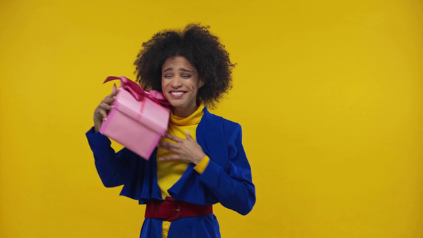 здивована афроамериканська дівчина приймає подарунок ізольовано на жовтому
 - Кадри, відео