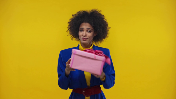 glücklich afrikanisch-amerikanische Mädchen schüttelt Geschenk isoliert auf gelb - Filmmaterial, Video