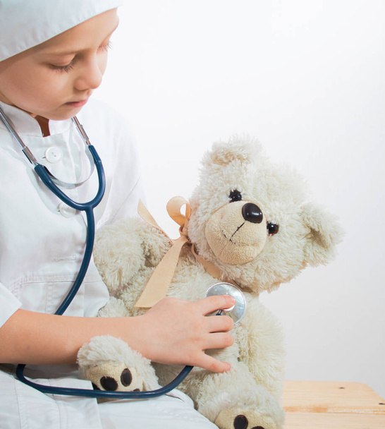 Cute kid boy playing doctor with plush toy at home. child boy playing doctor and curing plush toy indoors. isolated on white - Foto, Imagem