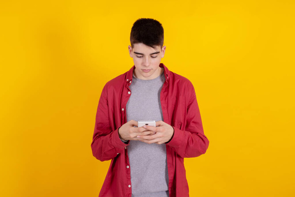 young teenage man with mobile phone isolated on background - Fotoğraf, Görsel