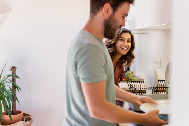 Couple partageant les tâches ménagères. Femme heureuse regardant l'homme laver la vaisselle
.  - Photo, image