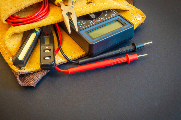 Gran conjunto de herramientas en bolsa de gamuza sobre fondo negro preparado por un maestro electricista profesional antes de la reparación o construcción
 - Foto, imagen