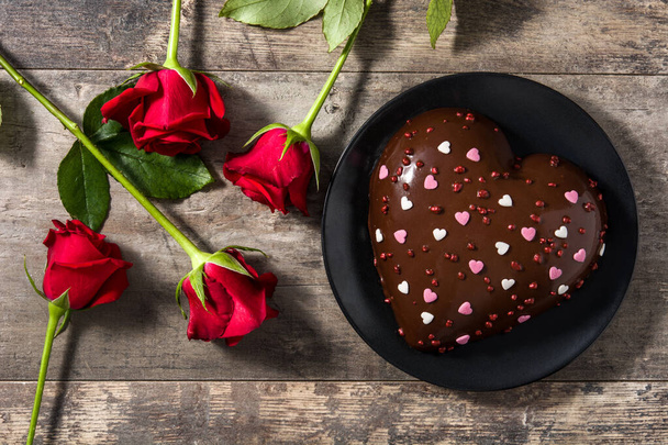 Pastel en forma de corazón y rosas rojas para el Día de San Valentín o el Día de la Madre en mesa de madera. Vista superior. Copiar espacio
 - Foto, Imagen