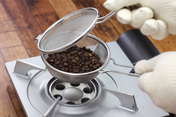 Roosteren van koffiebonen proces door handige rooster thuis; het controleren van roosteren staat van koffiebonen - Foto, afbeelding