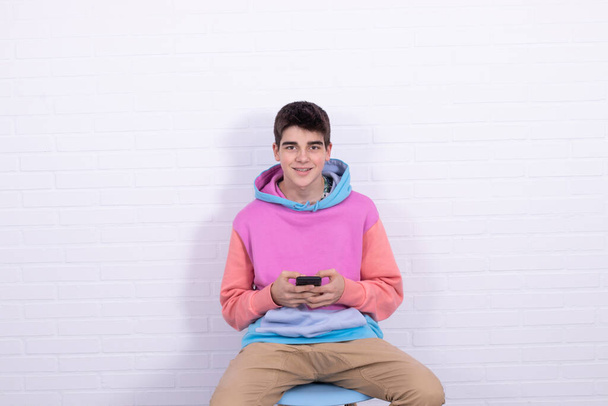 nuori teini-ikäinen poika tai opiskelija matkapuhelin istuu tuolilla
 - Valokuva, kuva