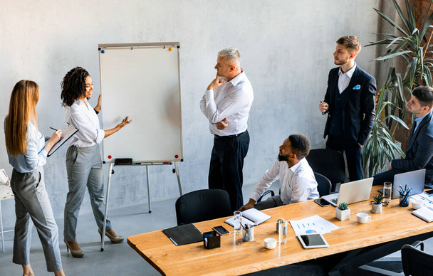 Черная предпринимательница представляет бизнес-идею коллегам в современном офисе
 - Фото, изображение