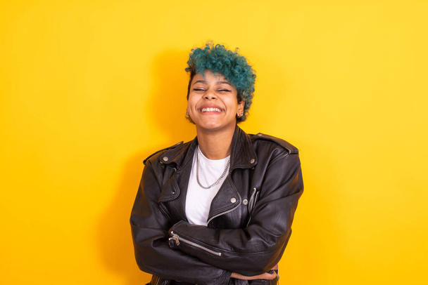 portrait of young afro american girl with blue hair and leather jacket isolated on yellow background - Foto, immagini