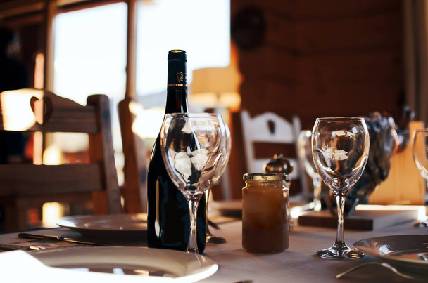 κόκκινο μπουκάλι κρασί και γυαλί στο τραπέζι σε εσωτερικούς χώρους - Φωτογραφία, εικόνα