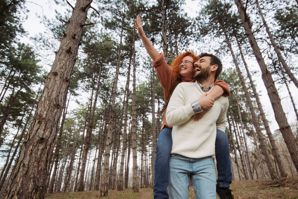 Joyeux couple profitant du printemps dans une belle forêt. Petit ami portant sa petite amie sur le dos. Printemps et parc public
. - Photo, image