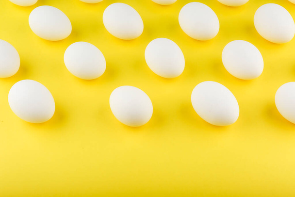 white chicken eggs on yellow background top view - Fotoğraf, Görsel