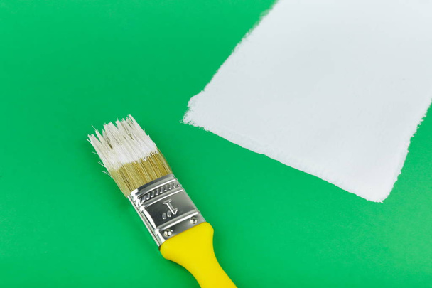 yellow paint brush and white stroke on a green background close up - Foto, Imagem