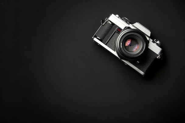 Классический 35-миллиметровый фотоаппарат на черном фоне стола
 - Фото, изображение