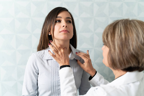 Кавказька жінка, яка відвідує сімейного лікаря для перевірки щитовидної залози. - Фото, зображення