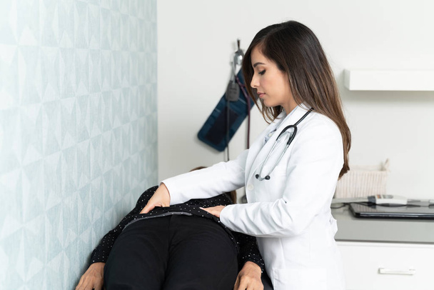 診察台に横たわっ高齢患者の胃を調べる婦人科医 - 写真・画像