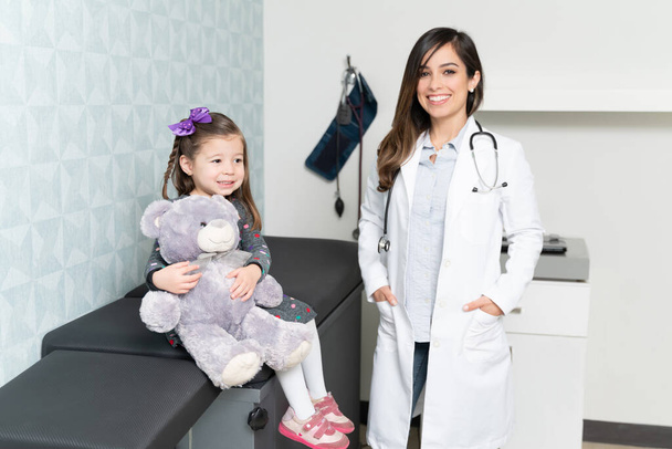 Pewny siebie biały kobieta pediatra z cute little girl w jej biurze - Zdjęcie, obraz