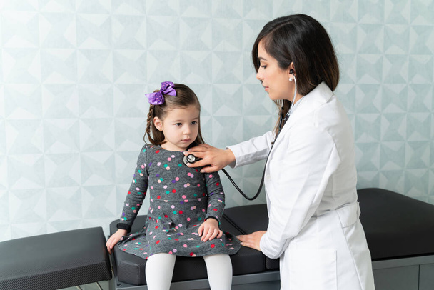 Female pediatrician examining cute girl with stethoscope during checkup - Fotografie, Obrázek