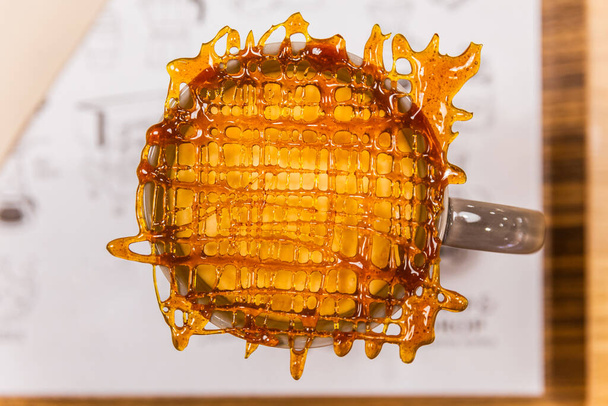 Gros plan sur la grille de caramel décorée sur une tasse de café macchiato au caramel chaud
. - Photo, image