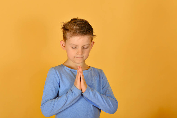 Chłopiec modli się na kolanach, religijne i pobożne dzieci. - Zdjęcie, obraz