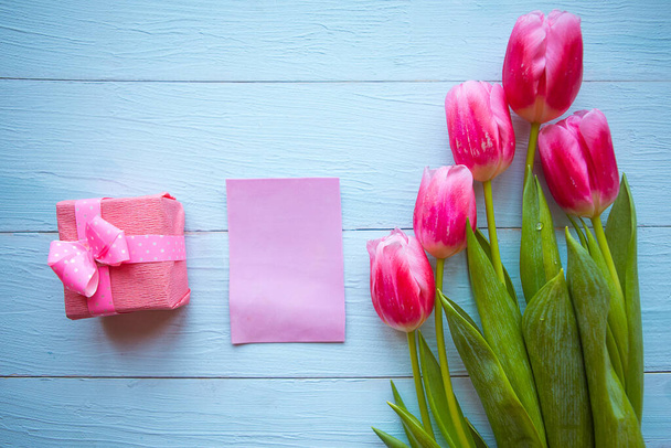 Roze tulpen en geschenkdoos op houten ondergrond. Pasen of Moederdag wenskaart - Foto, afbeelding