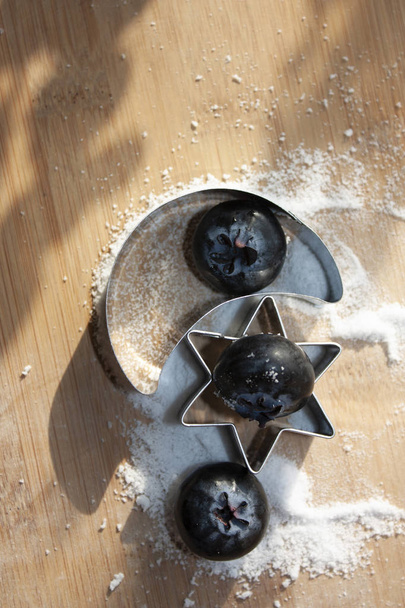 Blueberries eaten between moon and star figures that pose on sugar-free sweet granules for dessert - Photo, Image