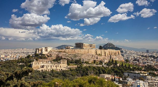 Athén, Görögország. Akropolisz és Parthenon templom. Szcenírozott kilátás az ókori Görögországra a Philopappos dombról. Athén városképe klasszikus görög romokkal, felhős kék égbolttal. - Fotó, kép