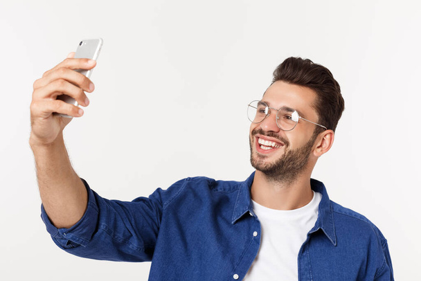 Portrét atraktivního mladého muže při selfie, jak stojí a ukazuje prstem na bílé pozadí. - Fotografie, Obrázek