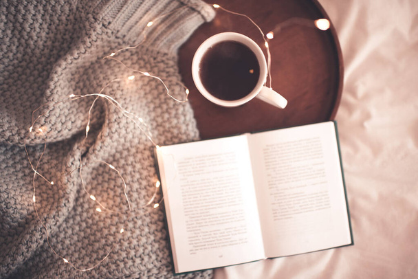 Nyitott könyv friss csésze kávé kötött mez az ágyban közeli. Téli ünnepek. - Jó reggelt! Újév..  - Fotó, kép