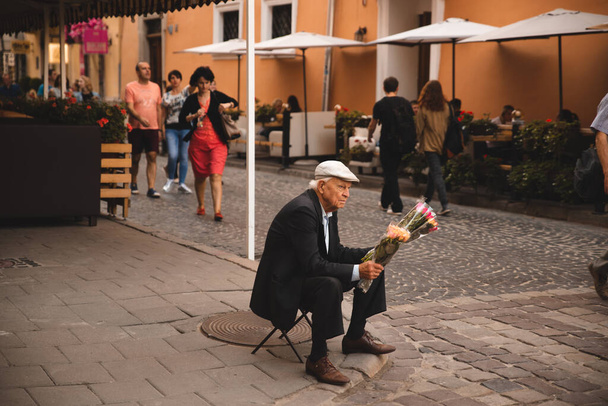 Lviv, Ucrânia - 18 de setembro de 2018: Velho vende flores na rua da cidade. hora de verão - Foto, Imagem