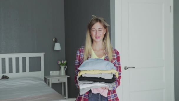 Fiatal háziasszony kezében tiszta ruhák és a kamerába néz - Felvétel, videó