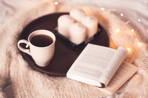 Taza de té con libro abierto y cabañas en la cama de cerca. Buenos días.
.  - Foto, Imagen
