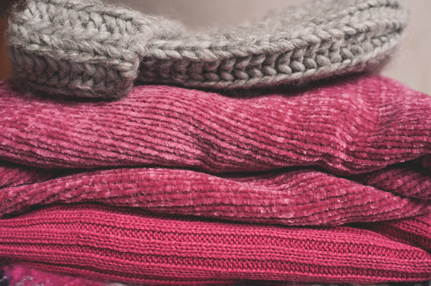 Clean cotton knitted sweaters and hat stacked in wardrobe closeup. Winter season.  - Photo, Image
