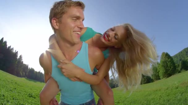 PORTRAIT : Homme joyeux donnant à sa copine blonde aux cheveux une promenade amusante
. - Séquence, vidéo