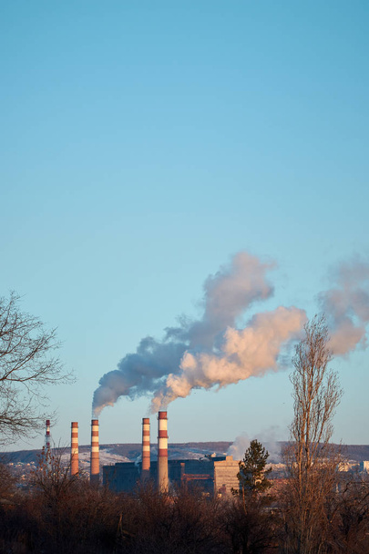 Завод испускает дым и смог из труб в солнечный день, загрязняющие вещества попадают в атмосферу. Экологическая катастрофа. Вредные выбросы. Химическая промышленность
 - Фото, изображение