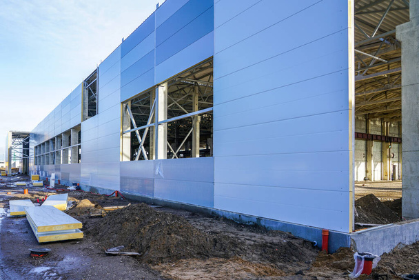 συναρμολόγηση τοίχου ενός νέου σύγχρονου κτιρίου εργοστασίου με χρήση χαλύβδινων σαντουιτσών - Φωτογραφία, εικόνα