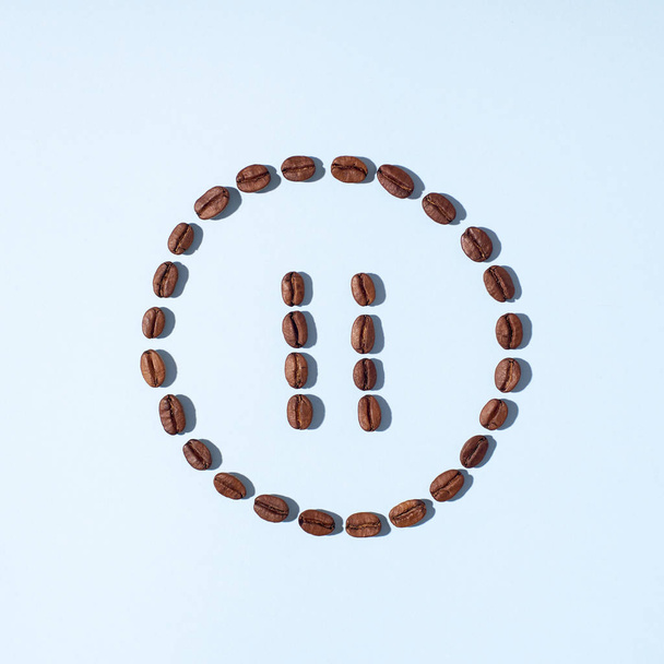 Pause symbol made from fresh roasted arabica coffee beans on light blue background. Creative minimal flat lay - Fotografie, Obrázek
