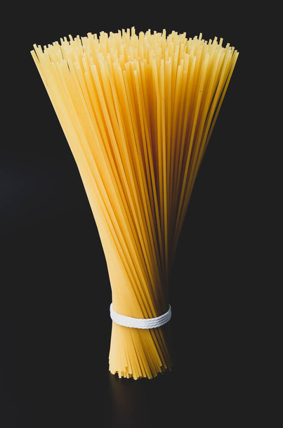 gebonden bos rauwe spaghetti op zwarte achtergrond - Foto, afbeelding